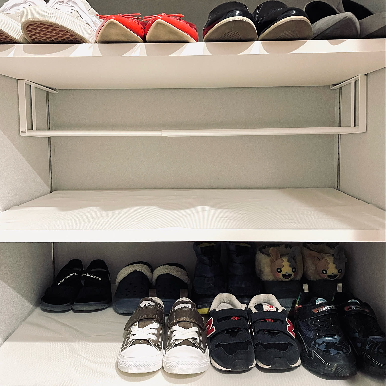 A floating white shoe rack used inside a shoe cabinet for active pairs.