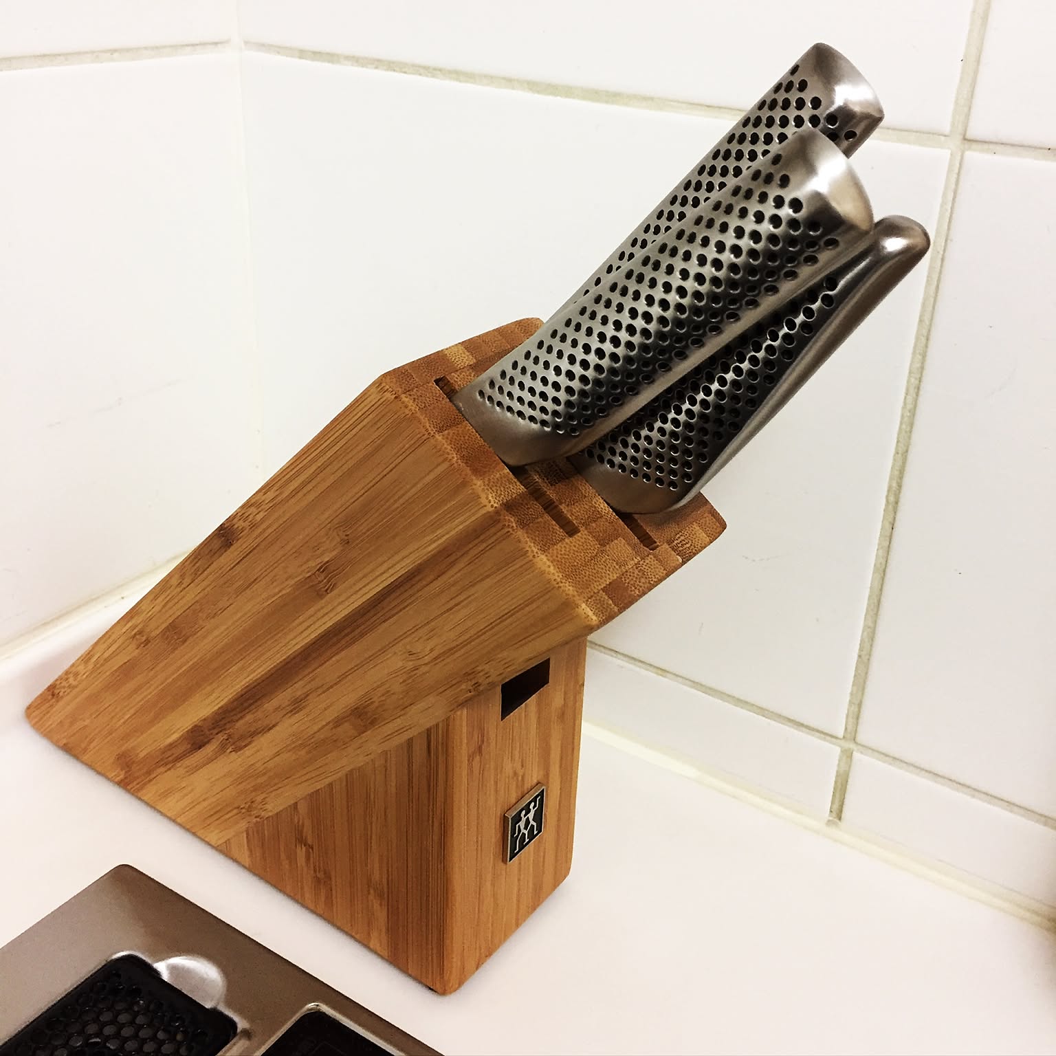 Knife block with several kitchen knives stored on a counter.