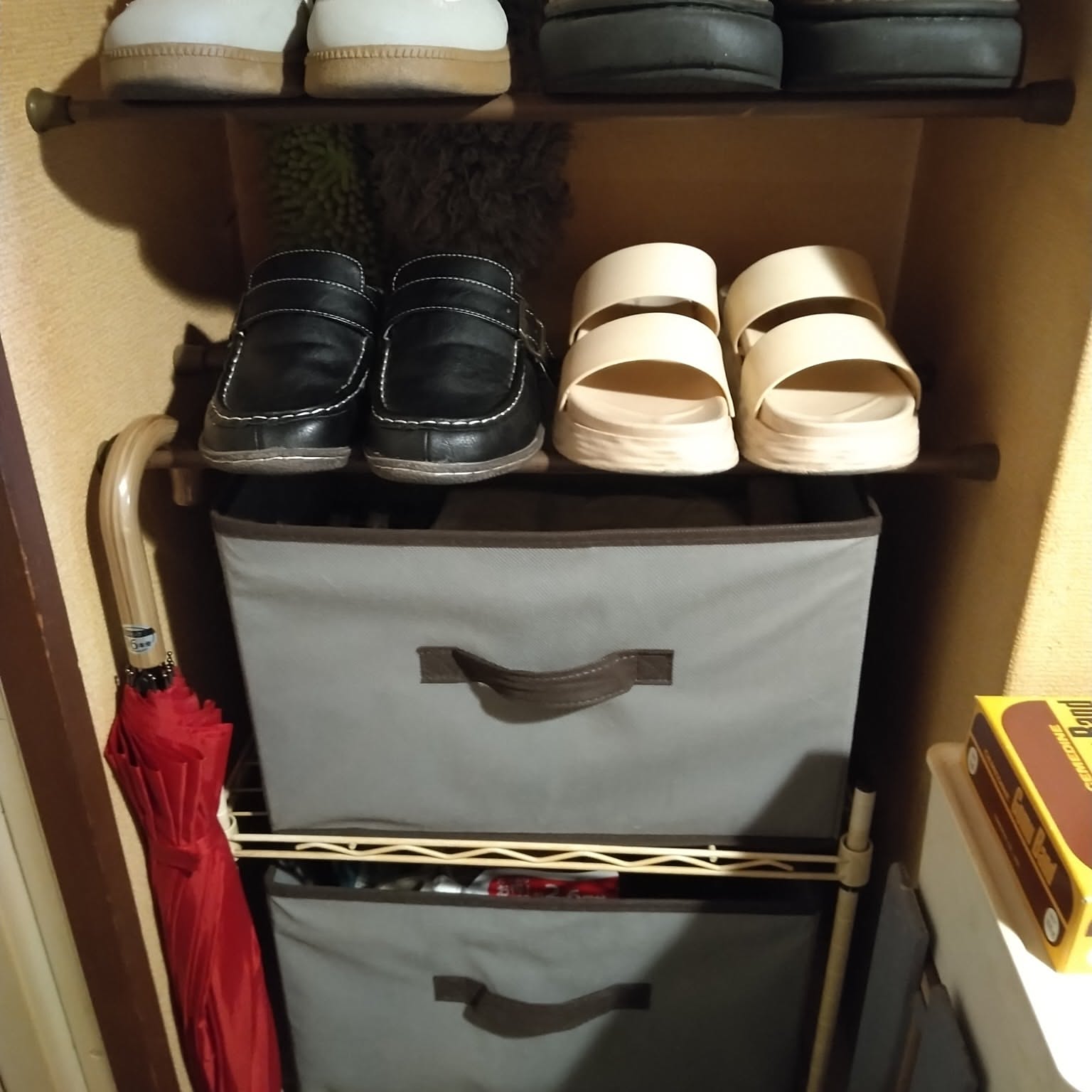 A very compact entryway shoe rack using boxes and shelves to hold shoes and household items.