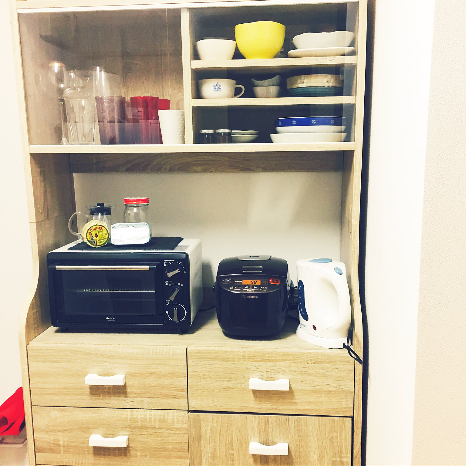 A compact brown Zojirushi 3-cup rice cooker stored beside a toaster and kettle.