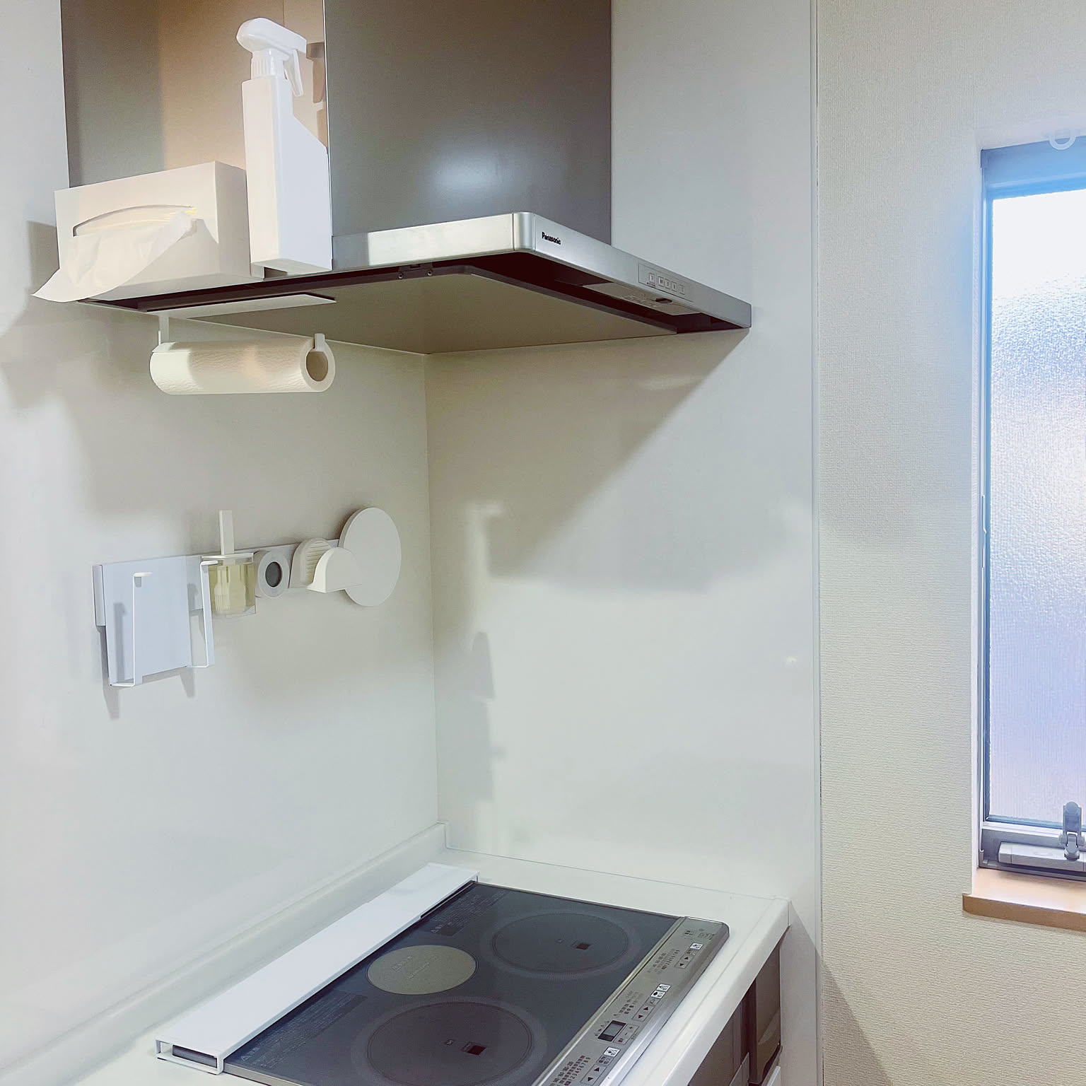 A clean white kitchen wall with Yamazaki Tower magnetic accessories including a tissue box holder, paper towel holder, and small magnetic tools near the range hood.