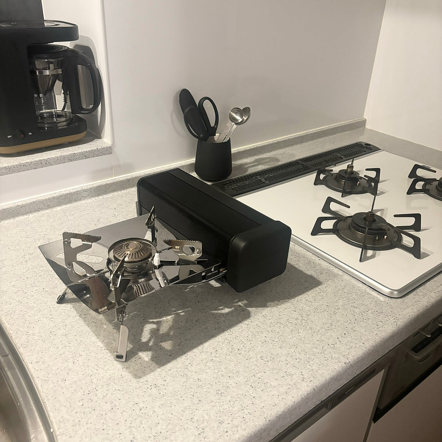 An Iwatani folding camp stove opened on a table with its case behind it.