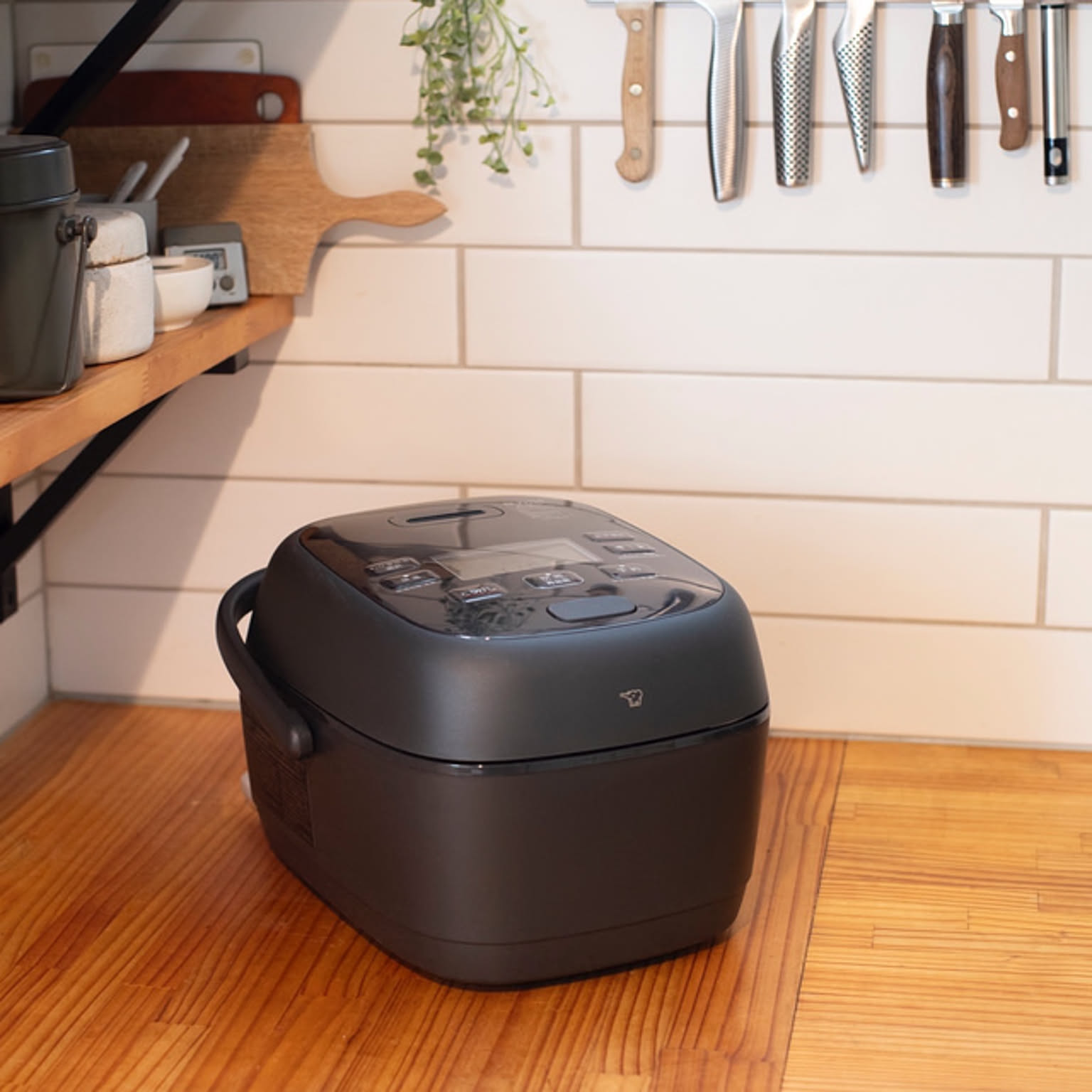 A black Zojirushi pressure IH rice cooker shown clearly on a kitchen counter.