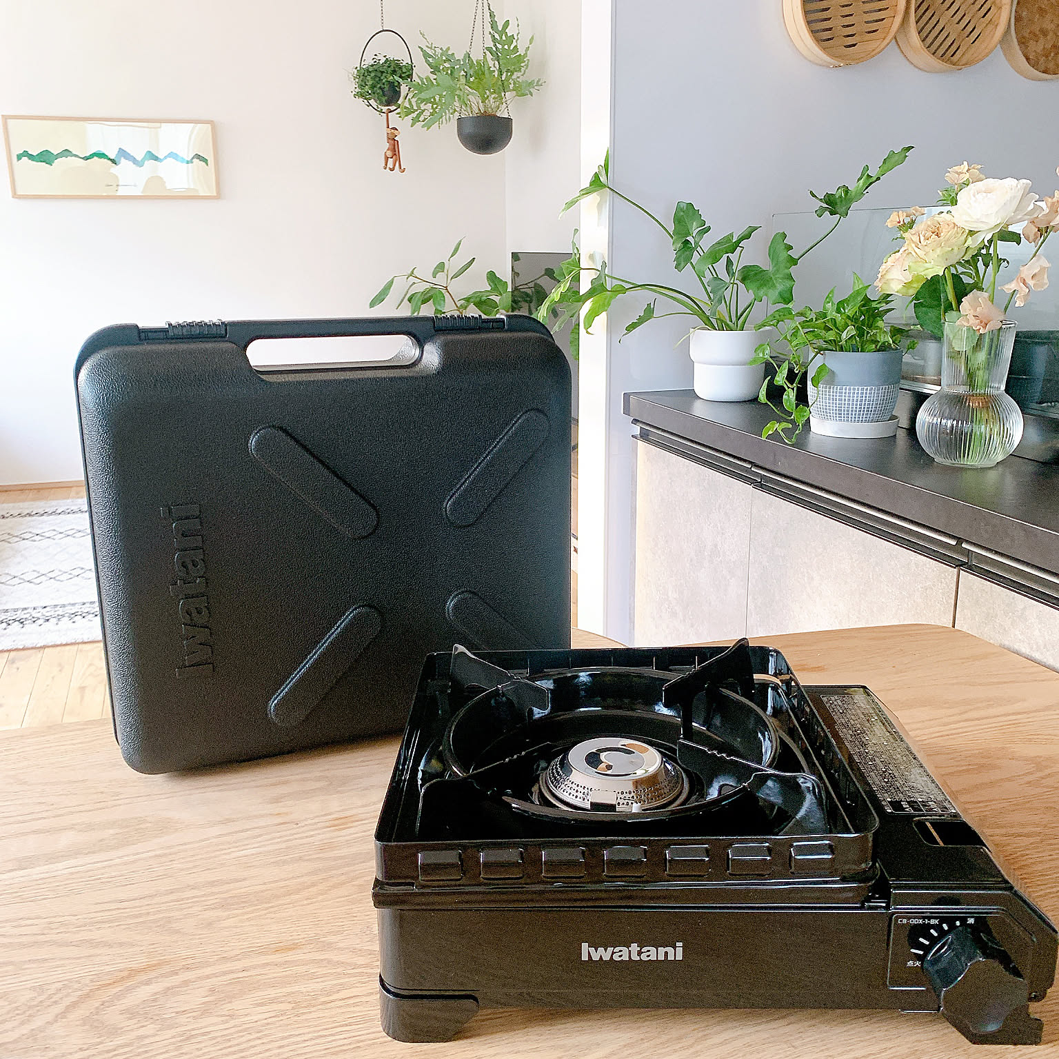 An Iwatani Tough Maru cassette stove on a table with its carrying case behind it.