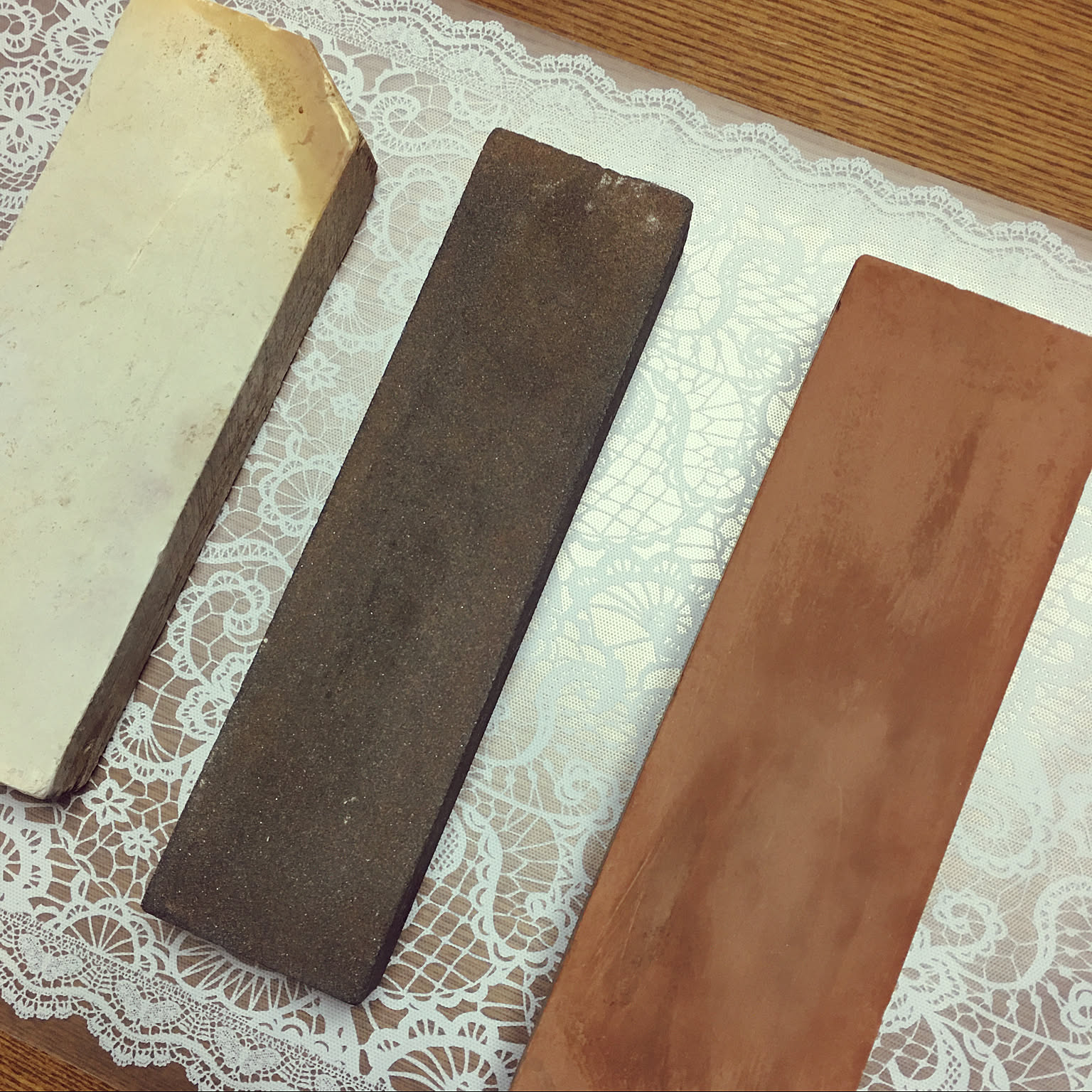 Three rectangular whetstones laid out for Japanese knife sharpening.