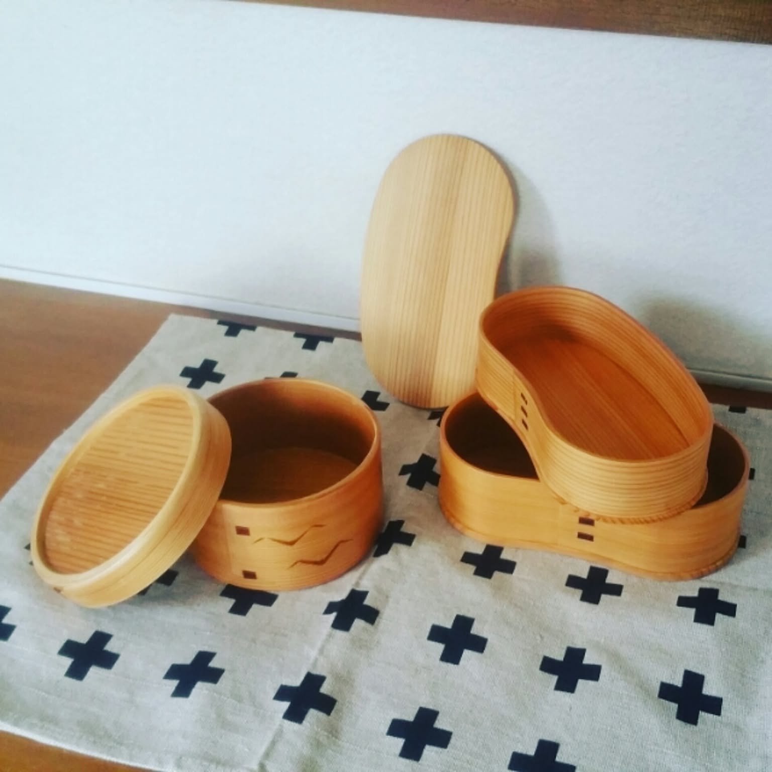 Several wooden magewappa bento boxes opened into separate bases and lids for air drying.