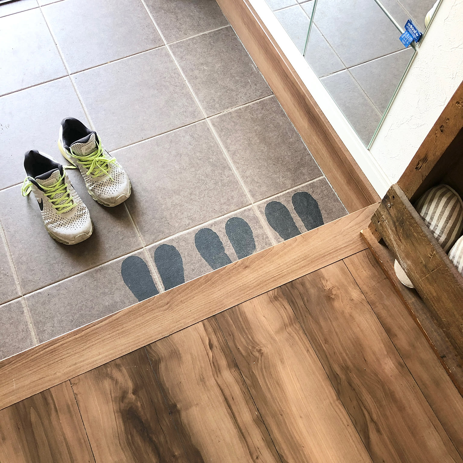 Footprint markers on an entryway floor showing where a child's shoes should be placed.