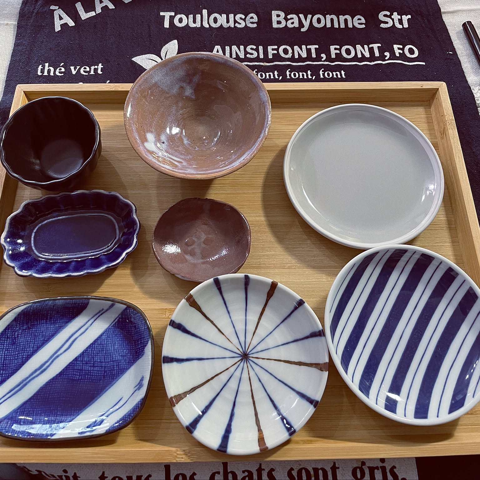 Japanese bowls and small plates in different depths and shapes on a tray.