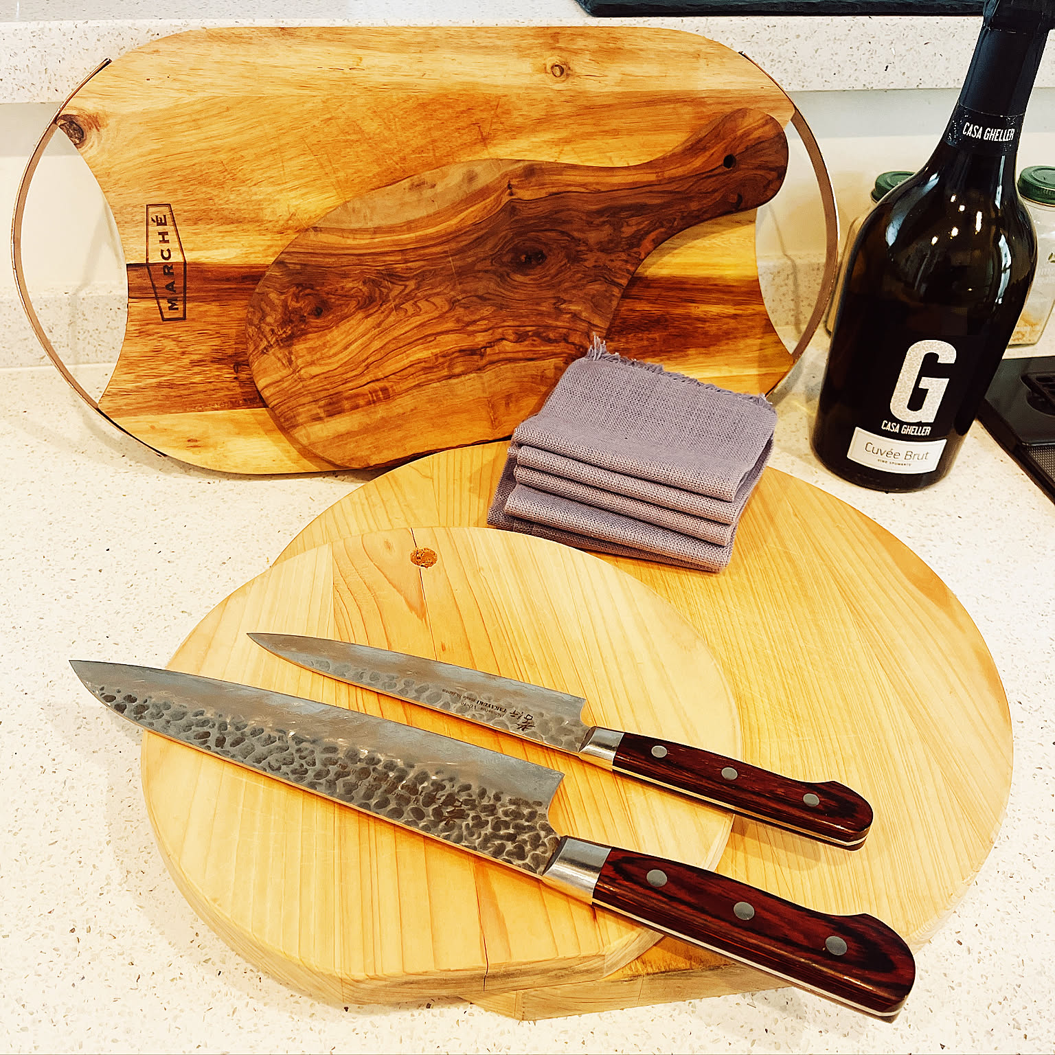 Two Japanese kitchen knives displayed with several wooden cutting boards.