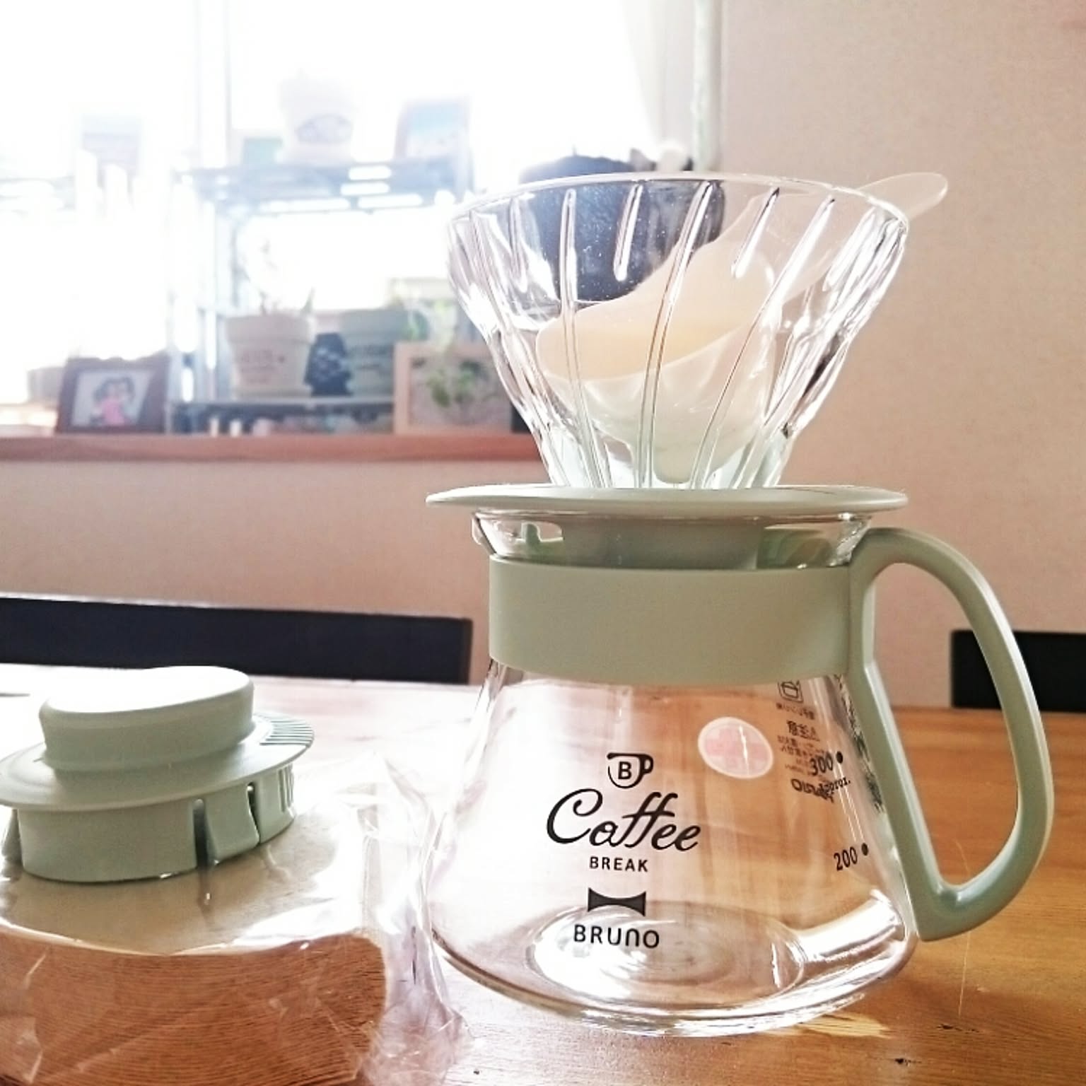 A clear glass V60-style dripper set over a matching glass server on a table.