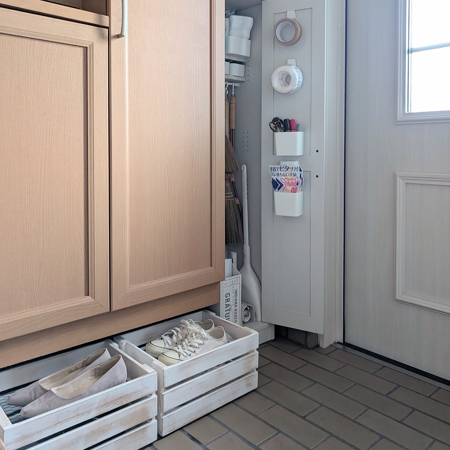 A compact Japanese entryway with shoe boxes, cleaning tools, and small door-side storage zones.