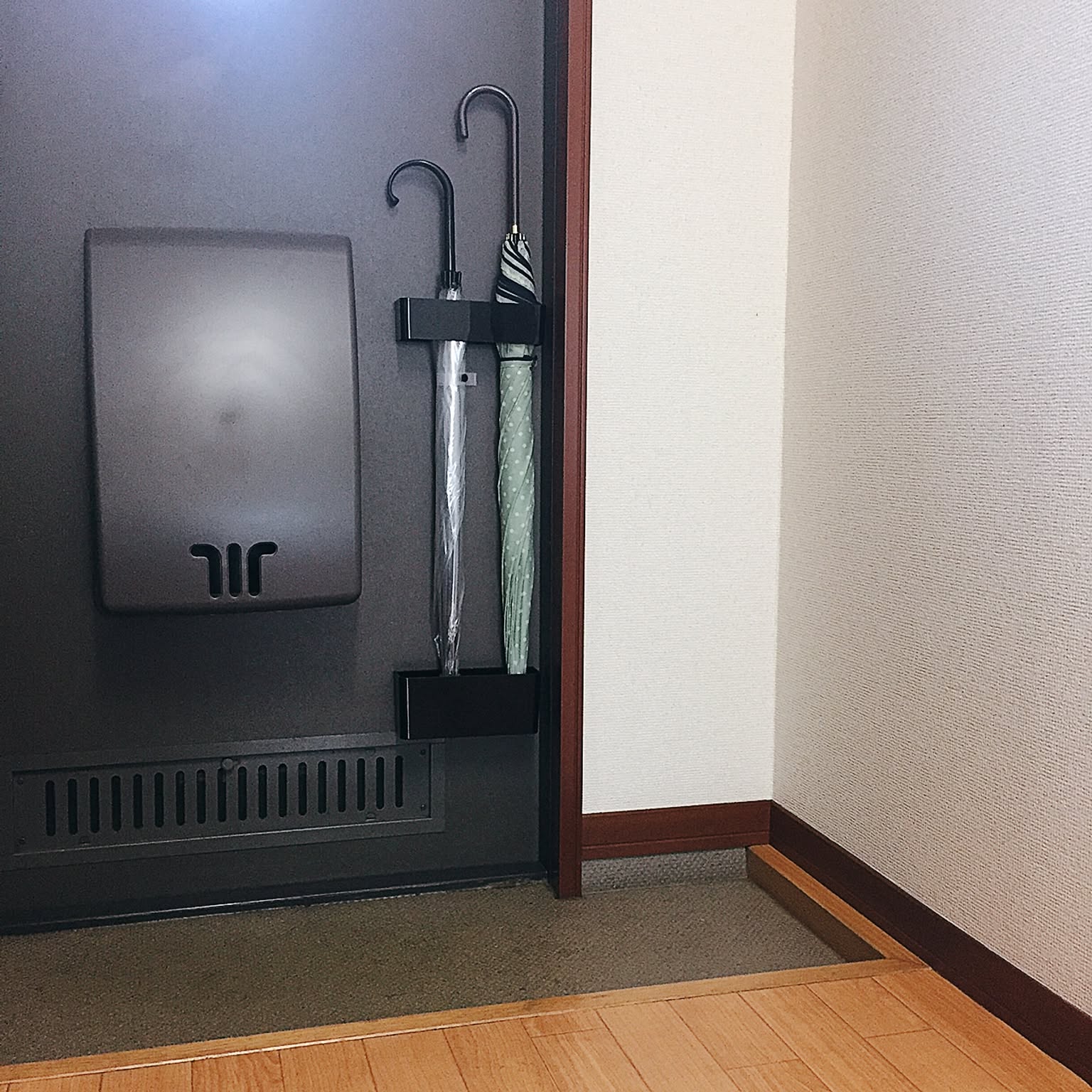 A magnetic umbrella stand mounted to a compact apartment entry door in a one-person Japanese home.