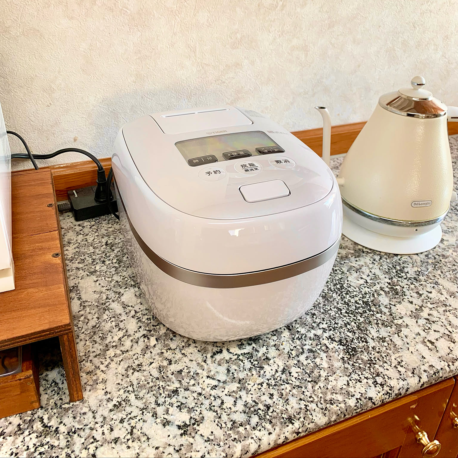 A white Tiger JPD-G060 3.5-cup rice cooker placed beside a white electric kettle.