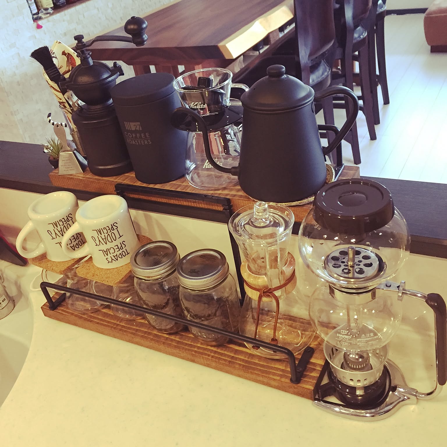 Tray-style coffee corner with kettle, server, grinder, jars, and cups.