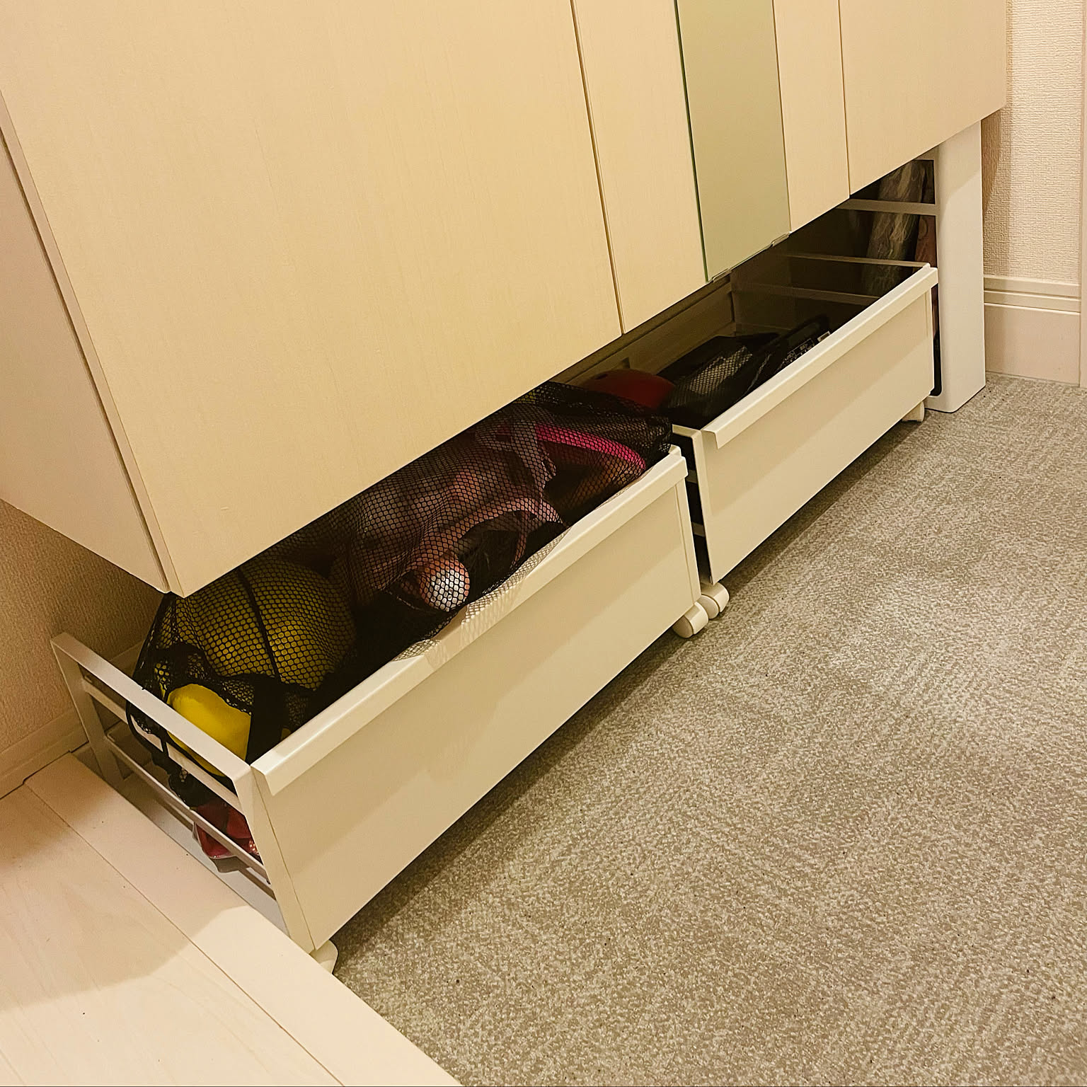 An under-shoebox wagon used for hidden entryway overflow in a Japanese rental apartment.