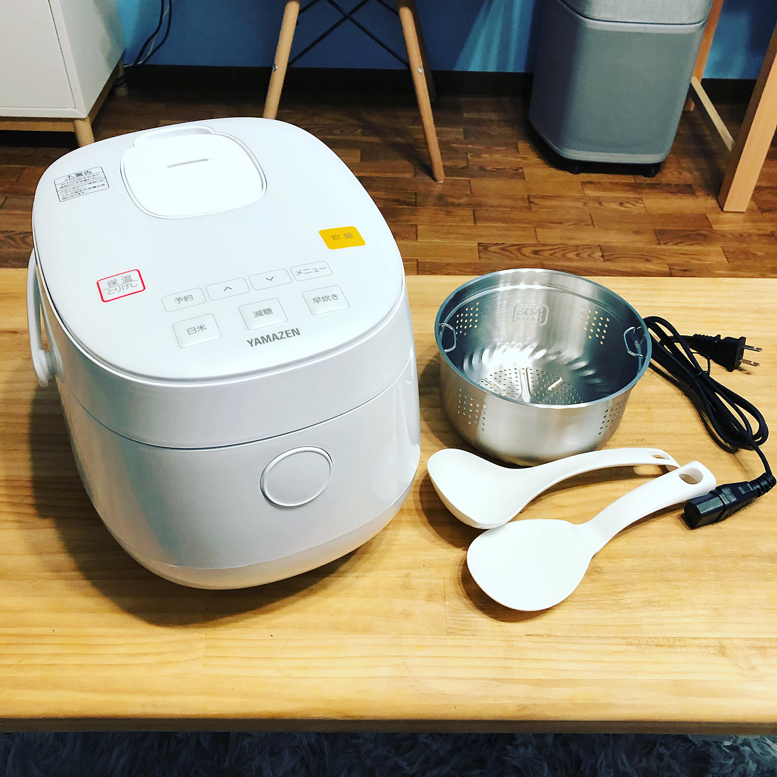 A white 3-cup rice cooker shown with its inner pot and rice paddles on a table.