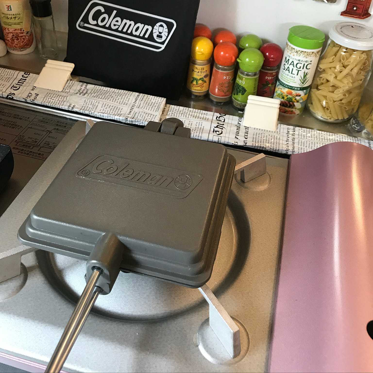 A slim Iwatani cassette stove kept in a kitchen as a power-outage cooking backup beside a hot sandwich maker.