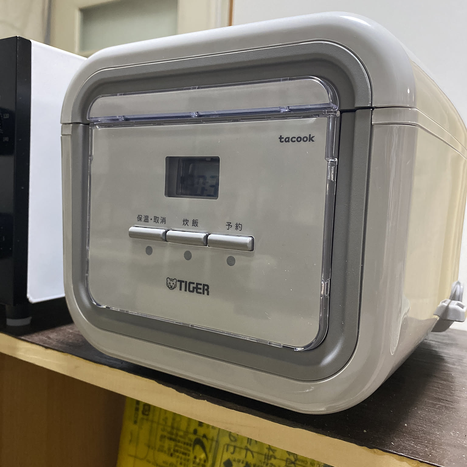 A gray Tiger tacook compact rice cooker shown close-up on a shelf.