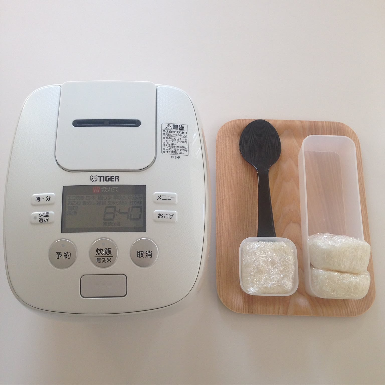 A white Tiger rice cooker shown beside frozen rice containers and a rice paddle.
