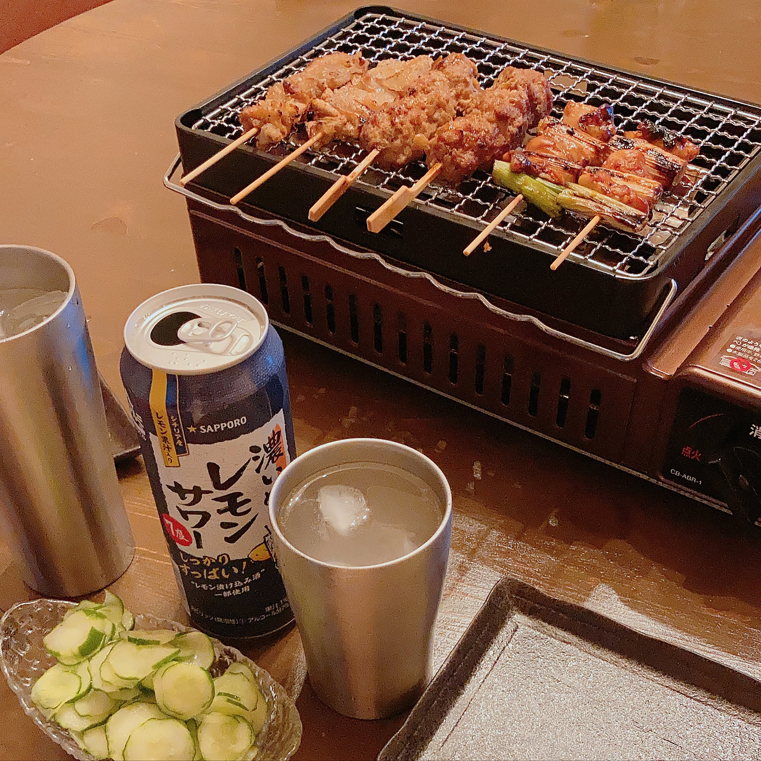 An Iwatani Aburiya robata grill cooking yakitori skewers on a tabletop.