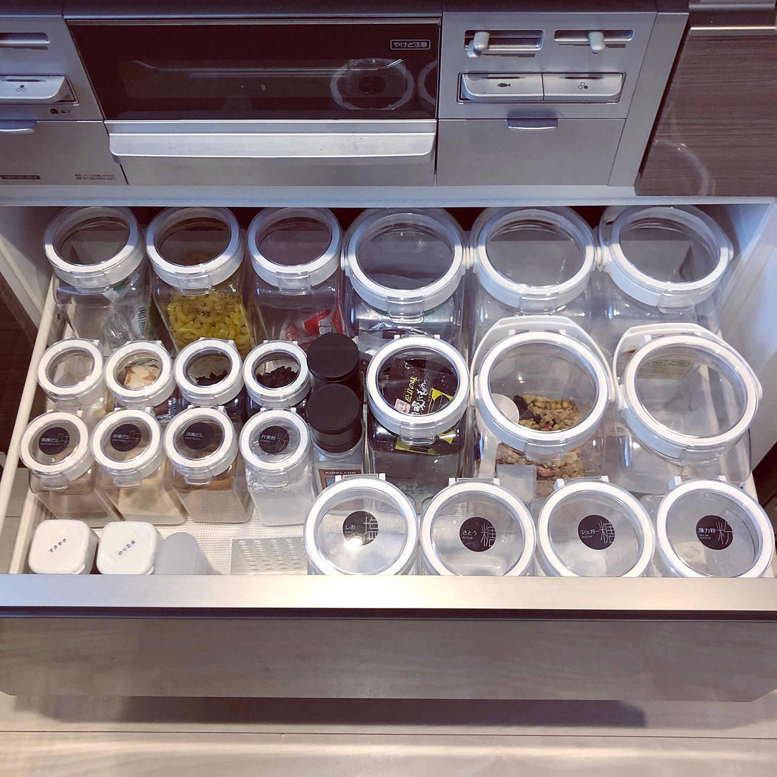 A deep kitchen drawer storing dry goods, seasonings, containers, packets, and boxed food in tidy rows.