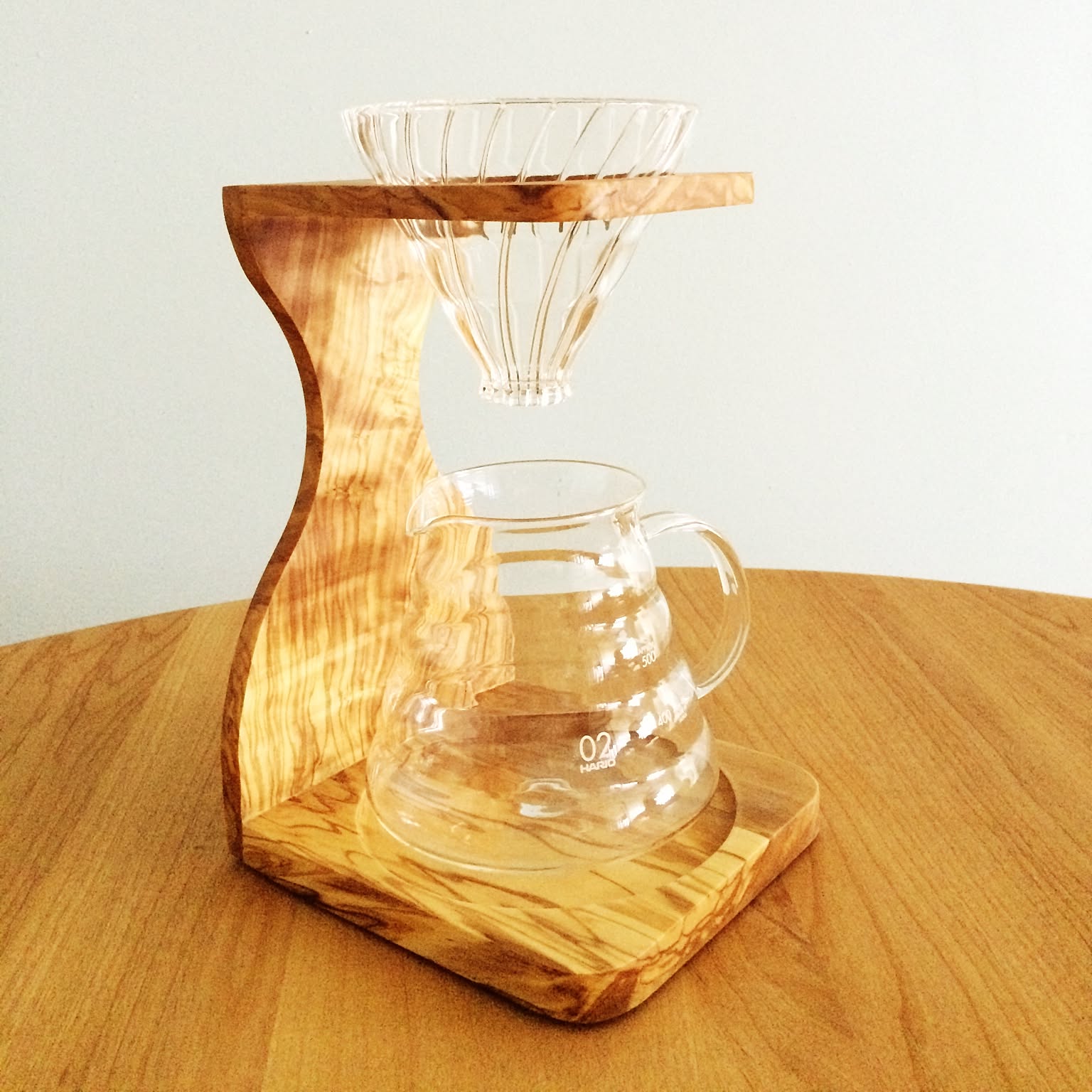 A Hario V60 olive-wood stand displayed as the focal point of a compact coffee station.