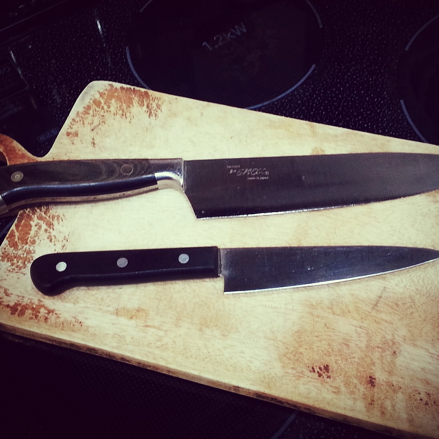 Long Japanese gyuto knife on a worn cutting board.