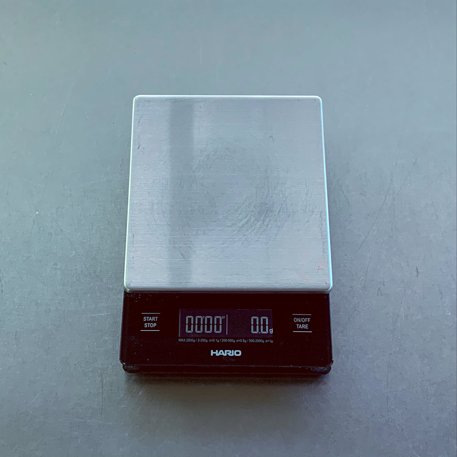 HARIO metal drip scale centered on a counter with the display and logo visible.