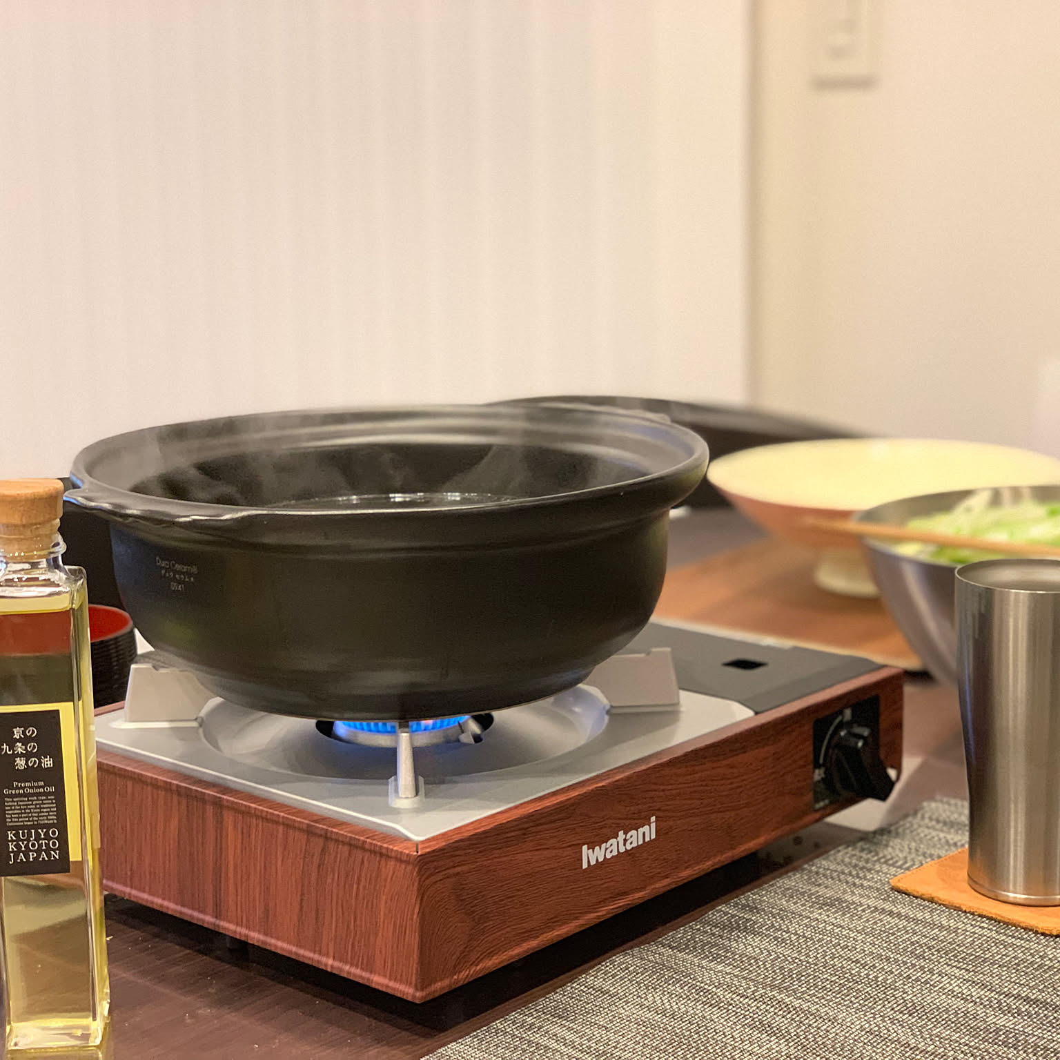 A woodgrain Iwatani cassette stove heating a pot during a tabletop meal.