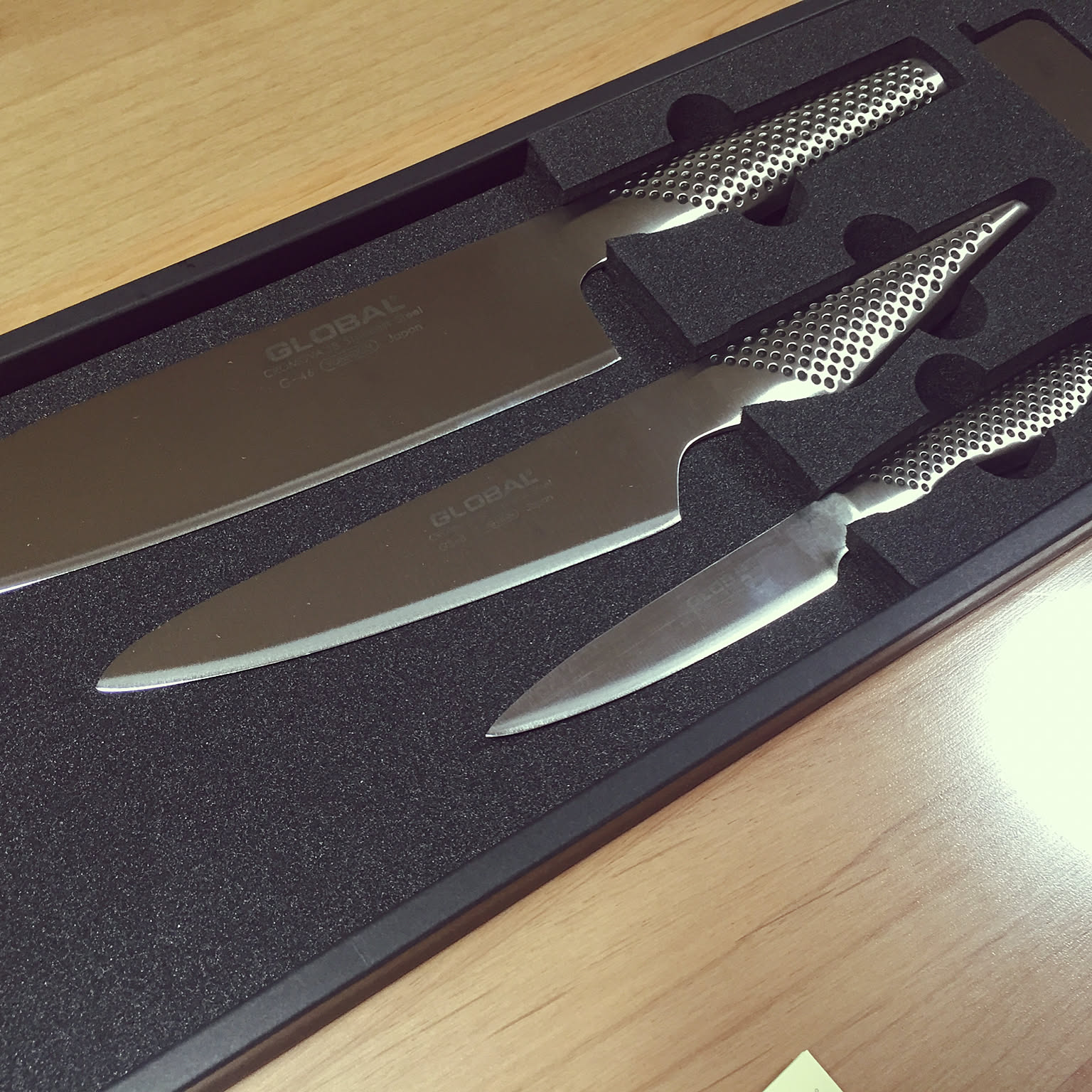 Global knife set with several Japanese kitchen knife shapes in a box.