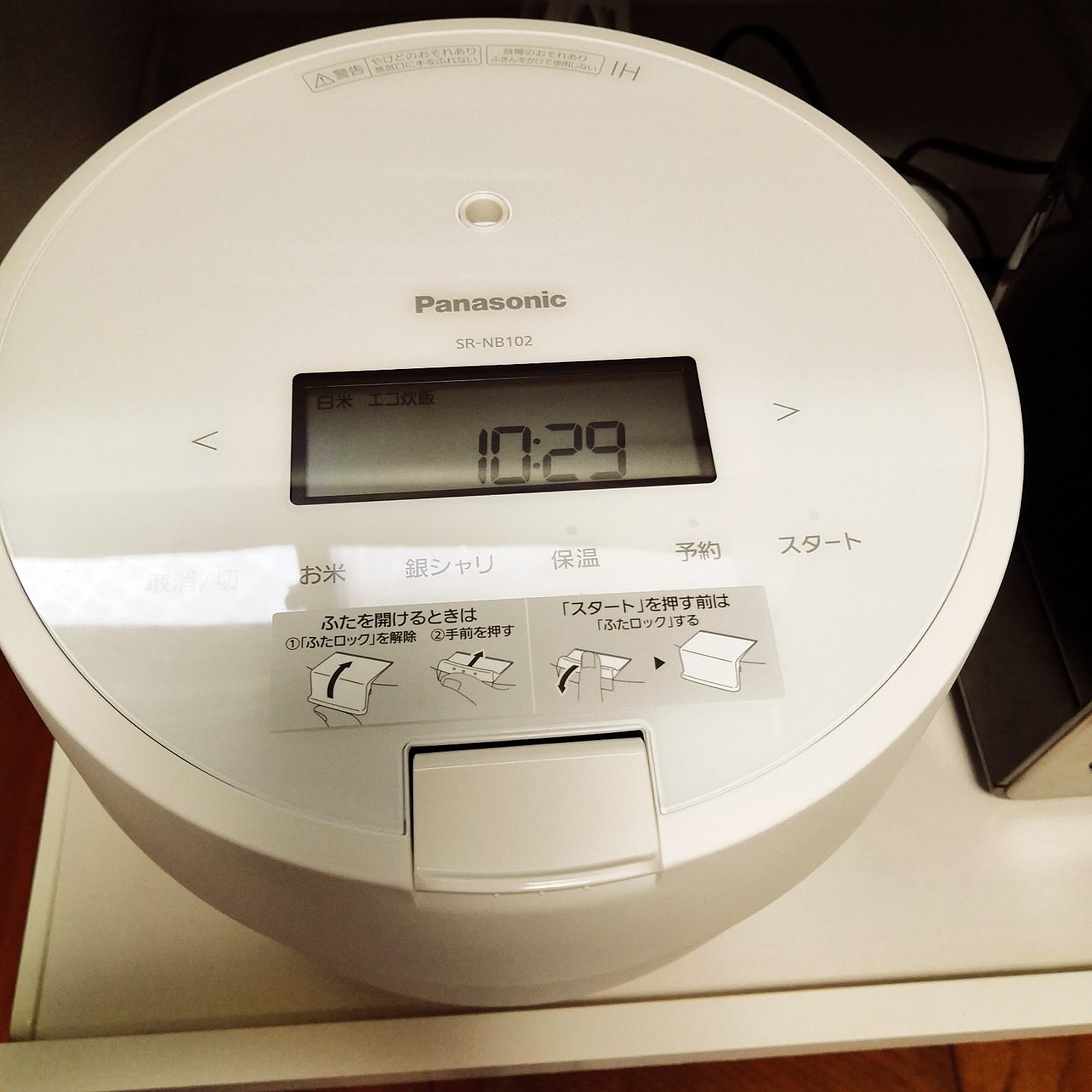A close-up of a white Panasonic rice cooker control panel and lid.
