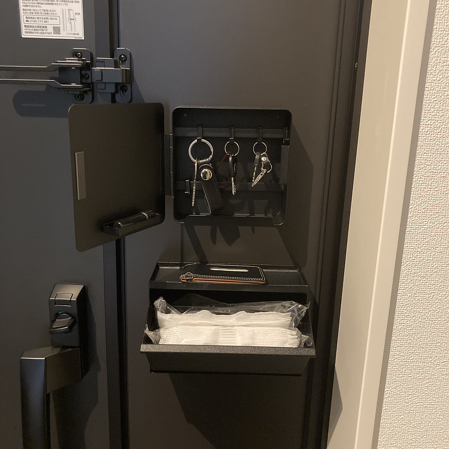 A magnetic key rack and mask storage station mounted inside a Japanese apartment entryway.