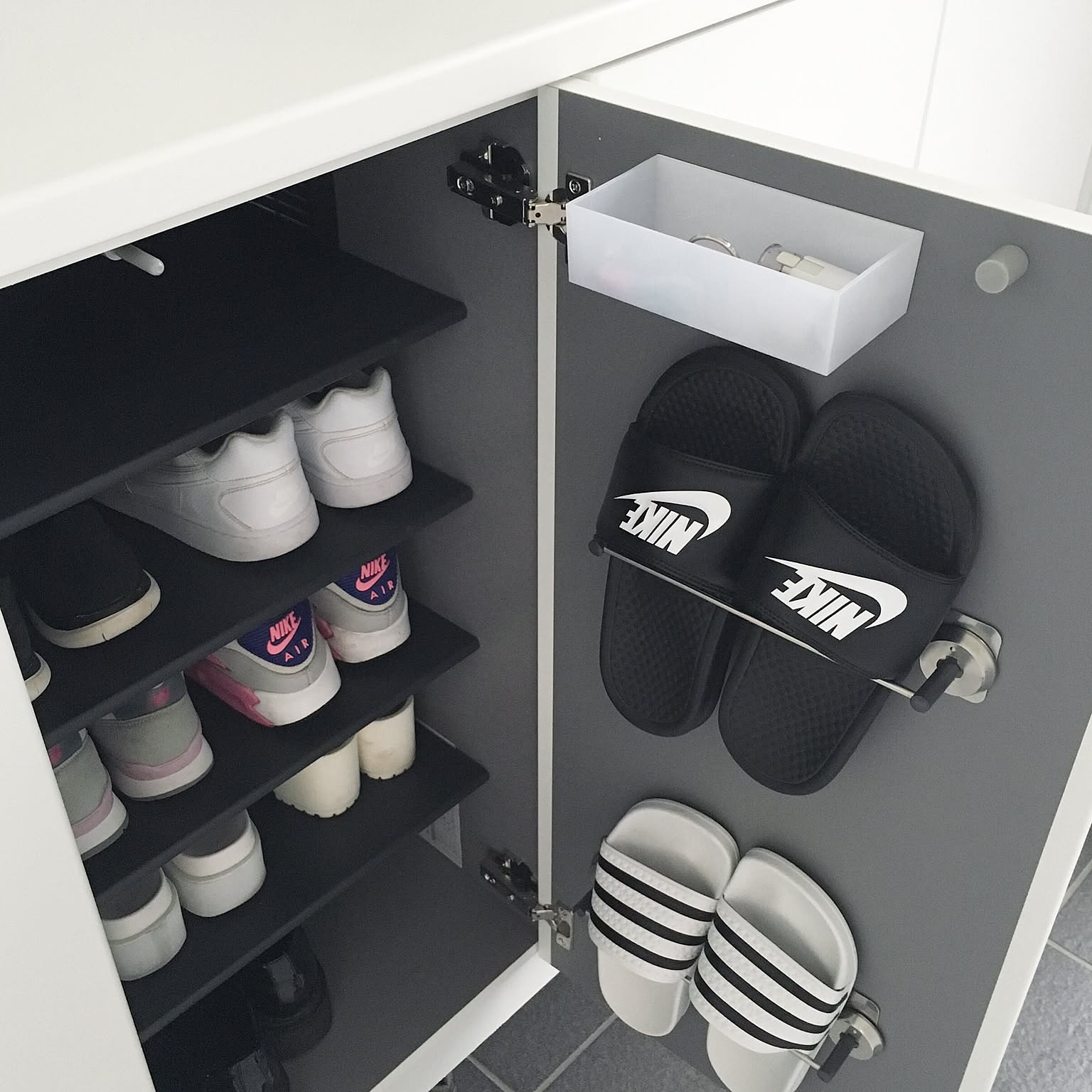 The inside of a shoe cabinet door used for slippers and a small tray while shoes stay organized on shelves.