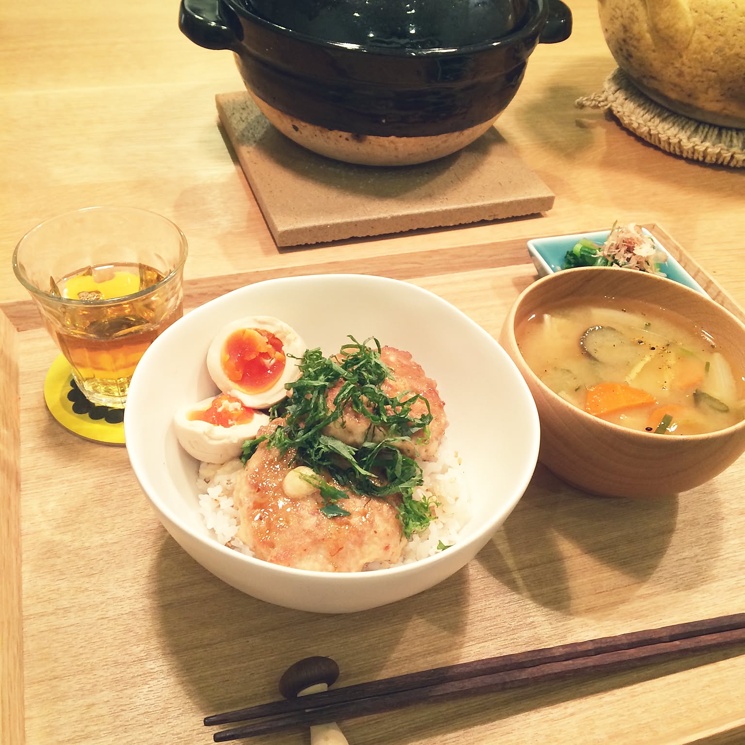 Japanese meal tray with a donburi rice bowl, soup bowl, side dish, chopsticks, and tea.