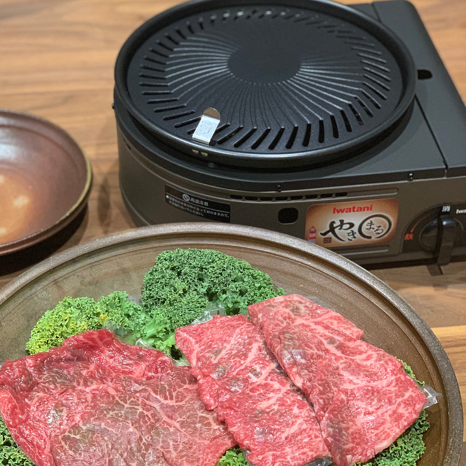 An Iwatani Yakimaru grill beside plates of meat before an indoor yakiniku meal.