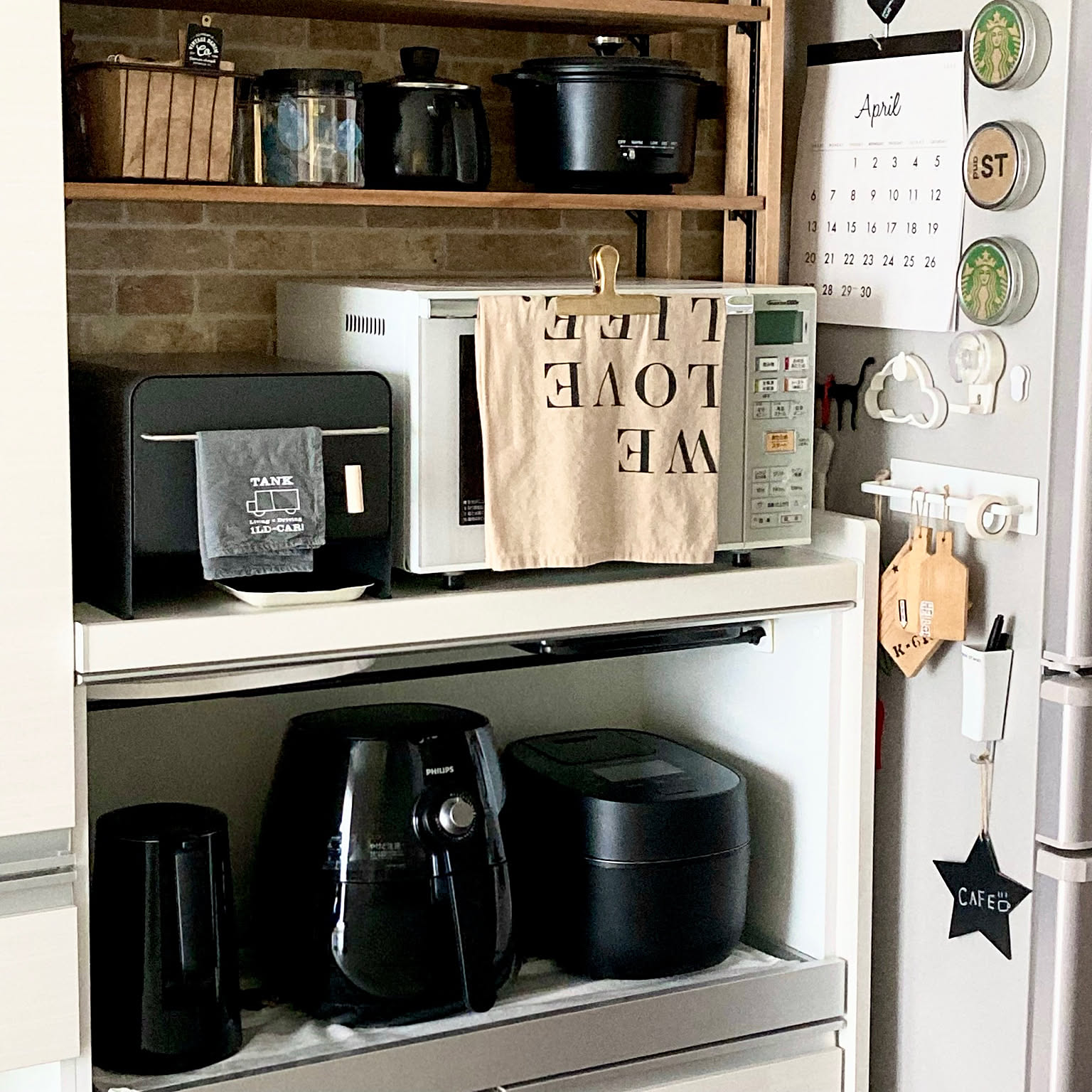 A black Panasonic rice cooker stored in a coordinated black appliance shelf.