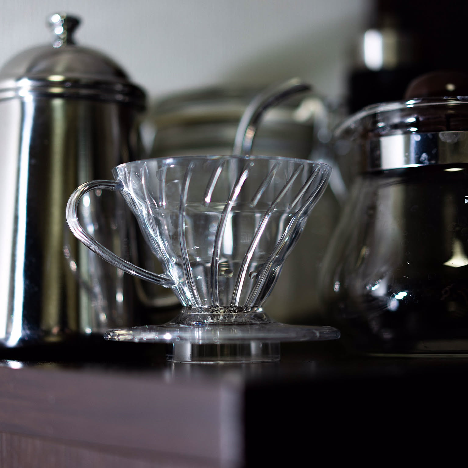 A Hario V60 plastic dripper displayed as the main subject in a compact Japanese coffee setup.