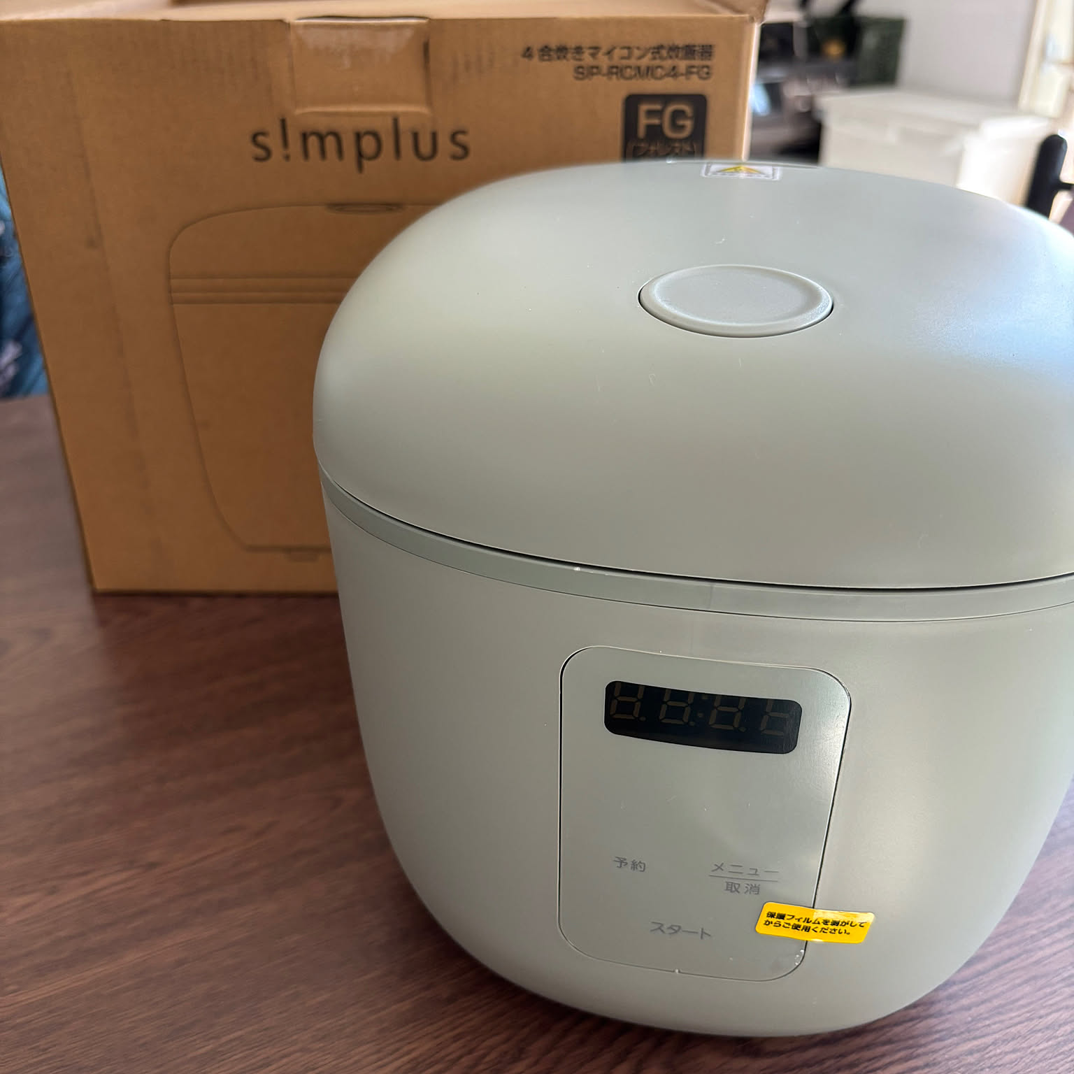 A compact white micom-style rice cooker shown prominently on a kitchen counter.