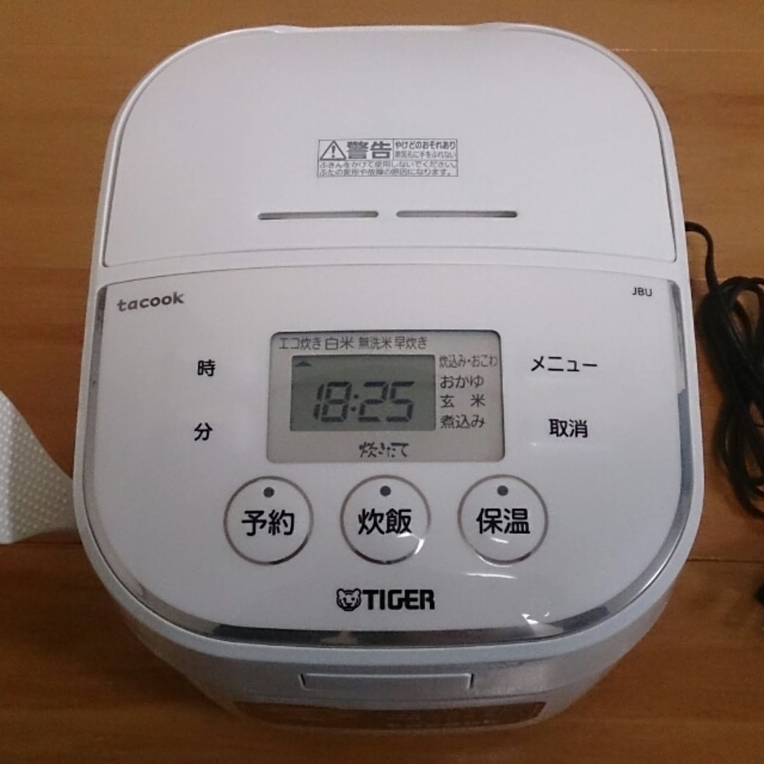 A white Tiger tacook rice cooker shown from above with large Japanese buttons.