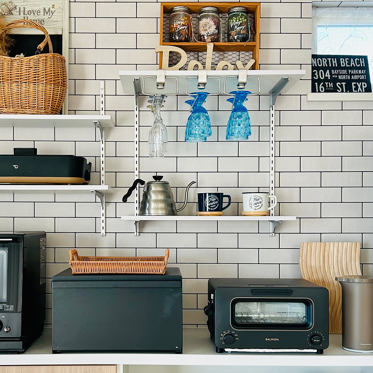 A HARIO V60 Buono drip kettle stored on a clean white kitchen shelf below hanging glasses.