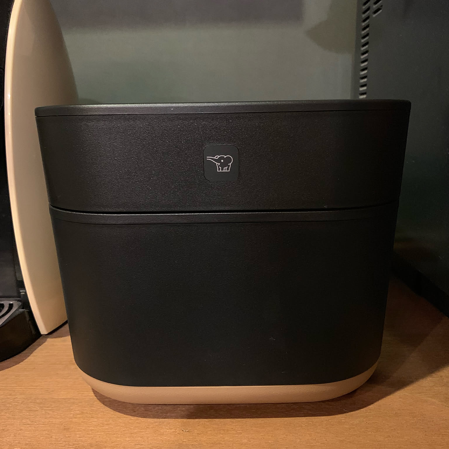 A black Zojirushi STAN. rice cooker shown close-up on a wooden kitchen shelf.