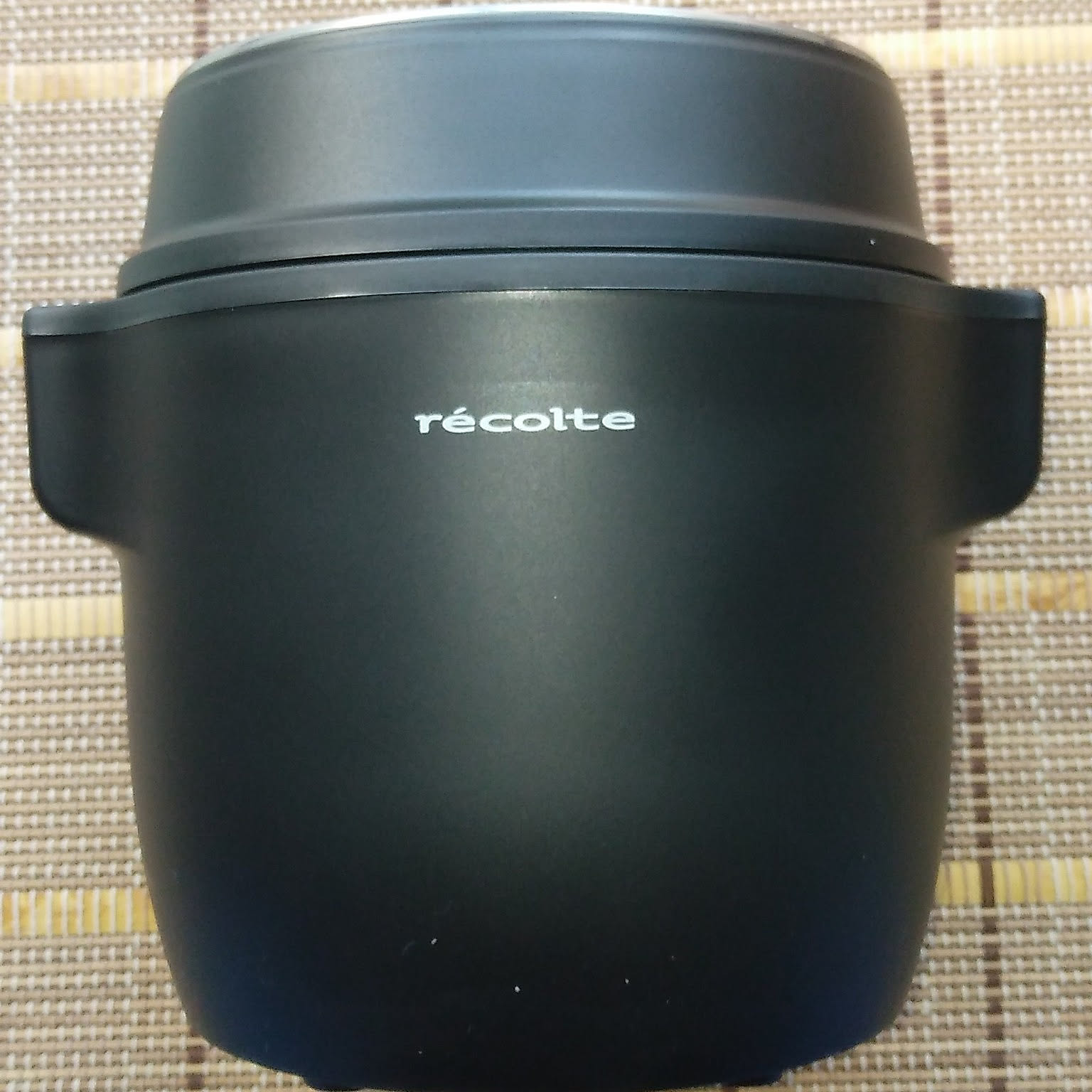 A black Recolte compact rice cooker shown close-up with the logo visible.