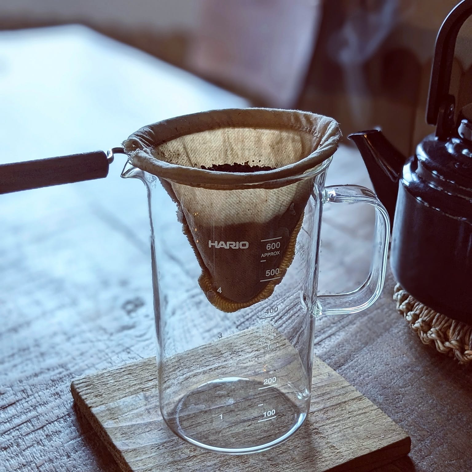 A Hario beaker server shown as the main subject in a compact hand-drip coffee setup.