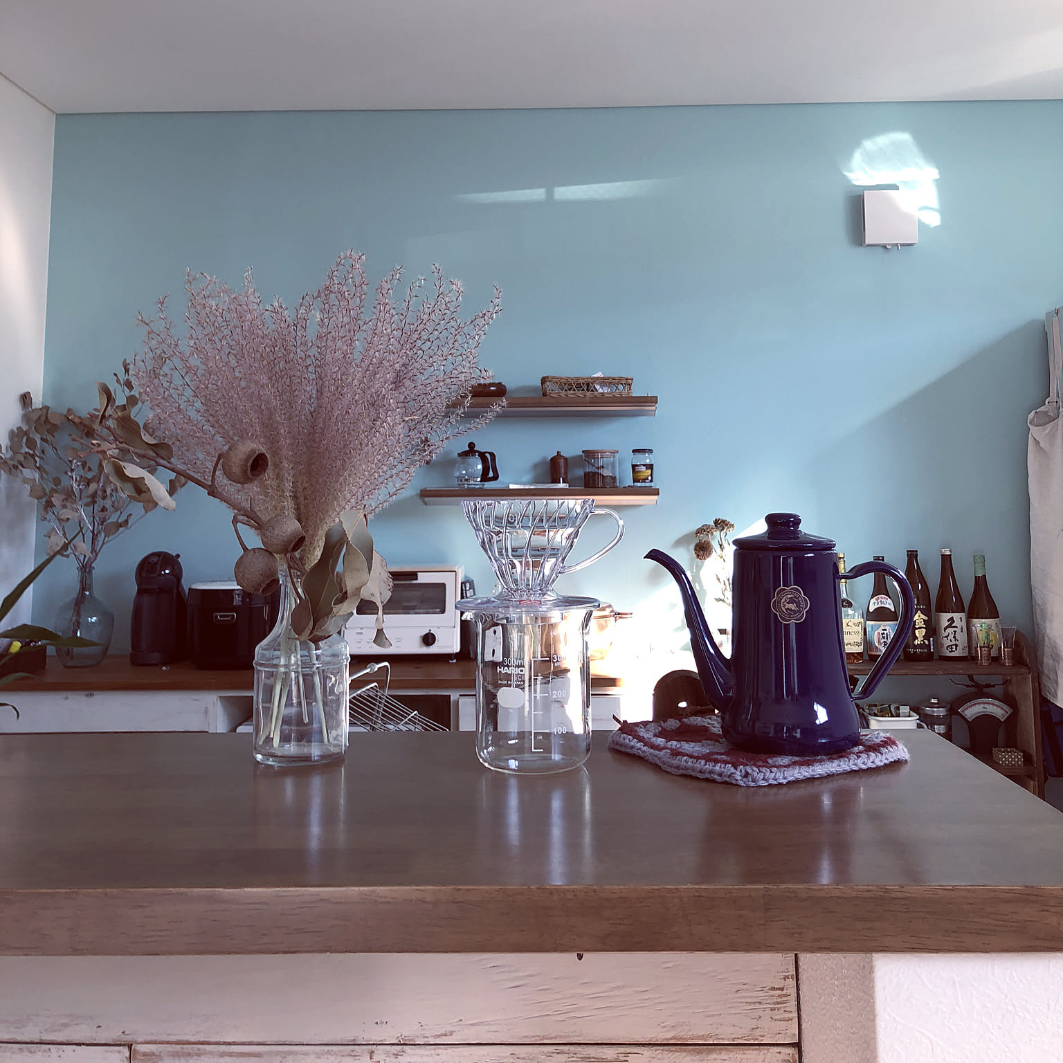 A clear HARIO V60 dripper set on a glass server beside a blue gooseneck kettle.