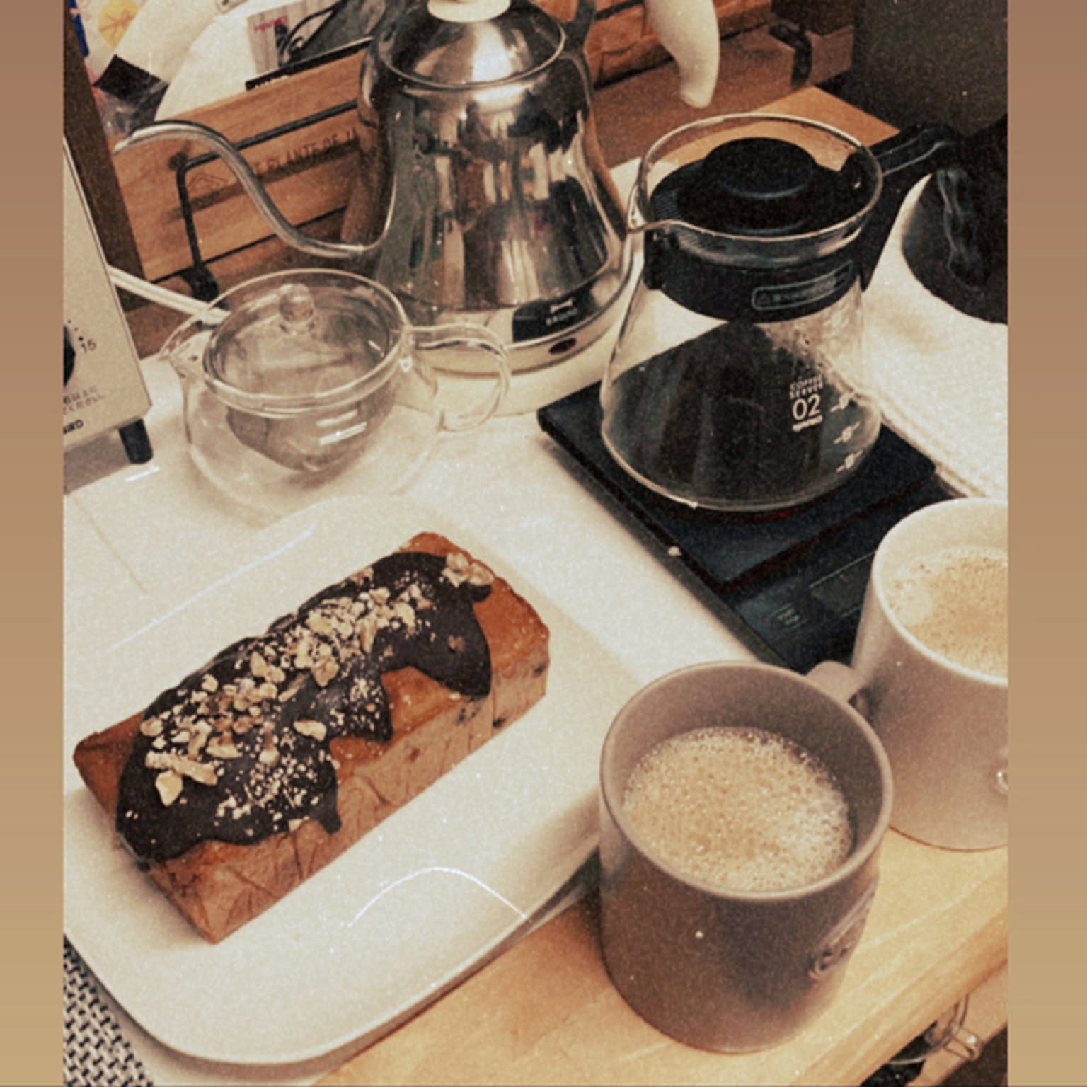 Pour-over setup with kettle, HARIO V60 server, drip scale, cups, and cake.