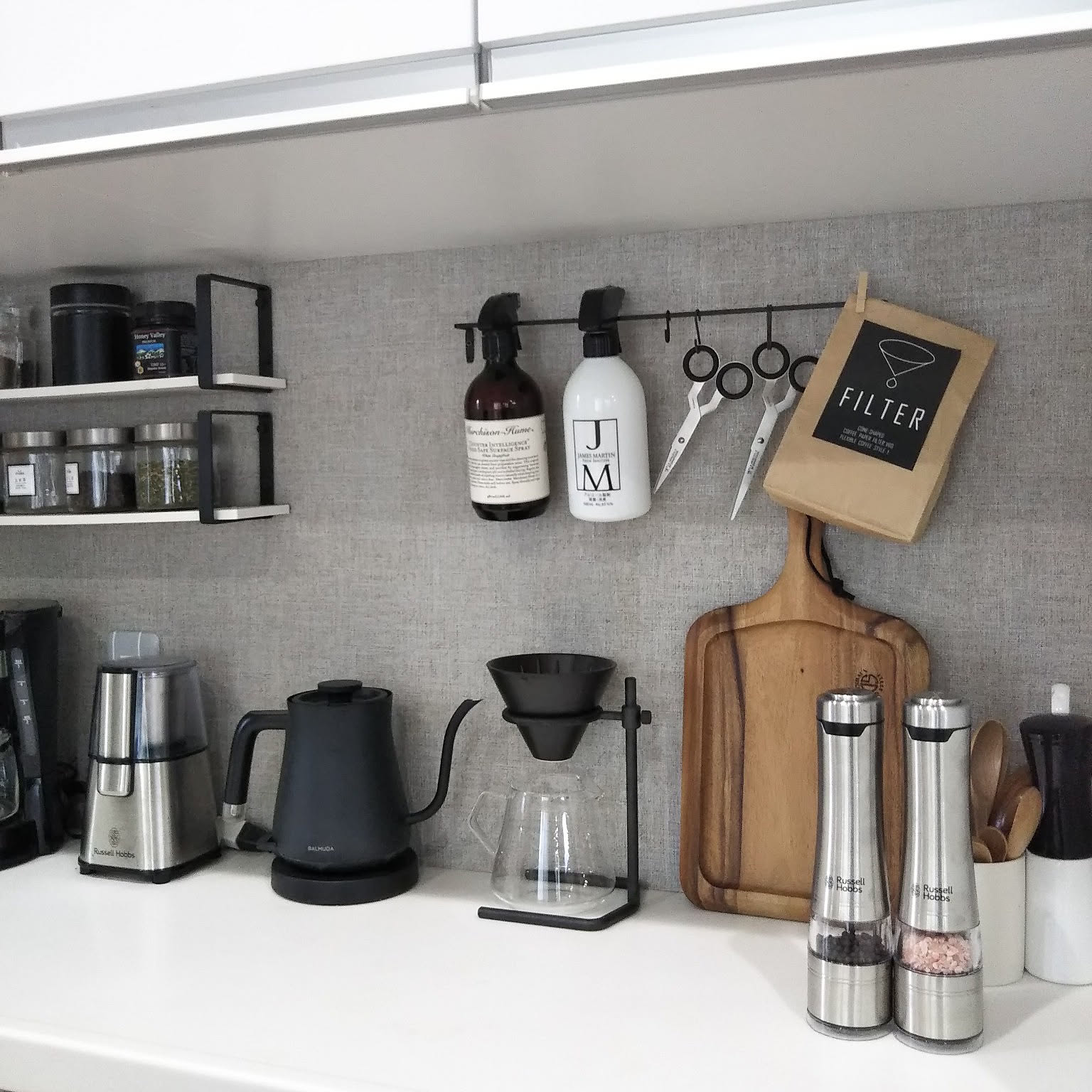 Compact Japanese coffee counter with grinder, kettle, dripper stand, and filter storage.
