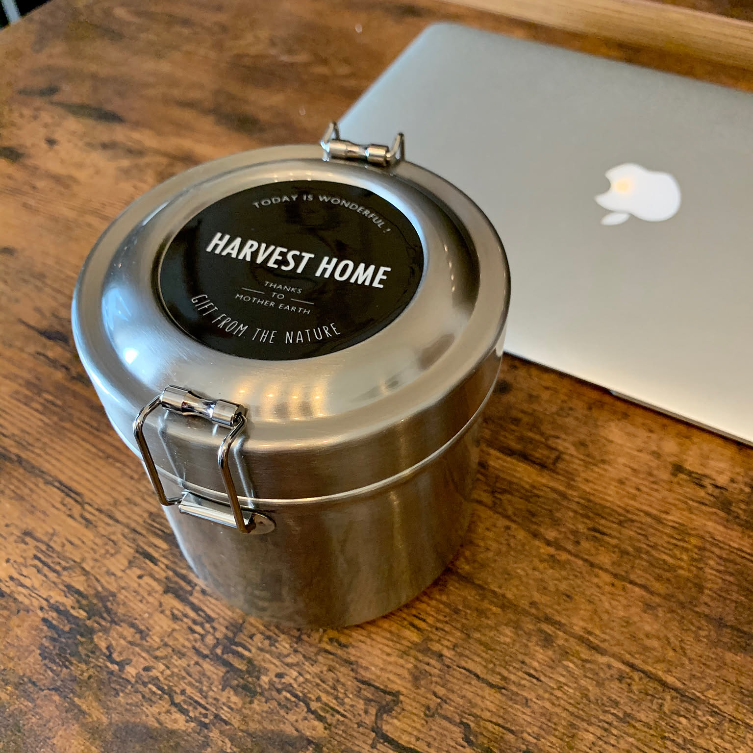 Round Skater STLB1-family vacuum stainless lunch box with two locking clips on a wooden desk.