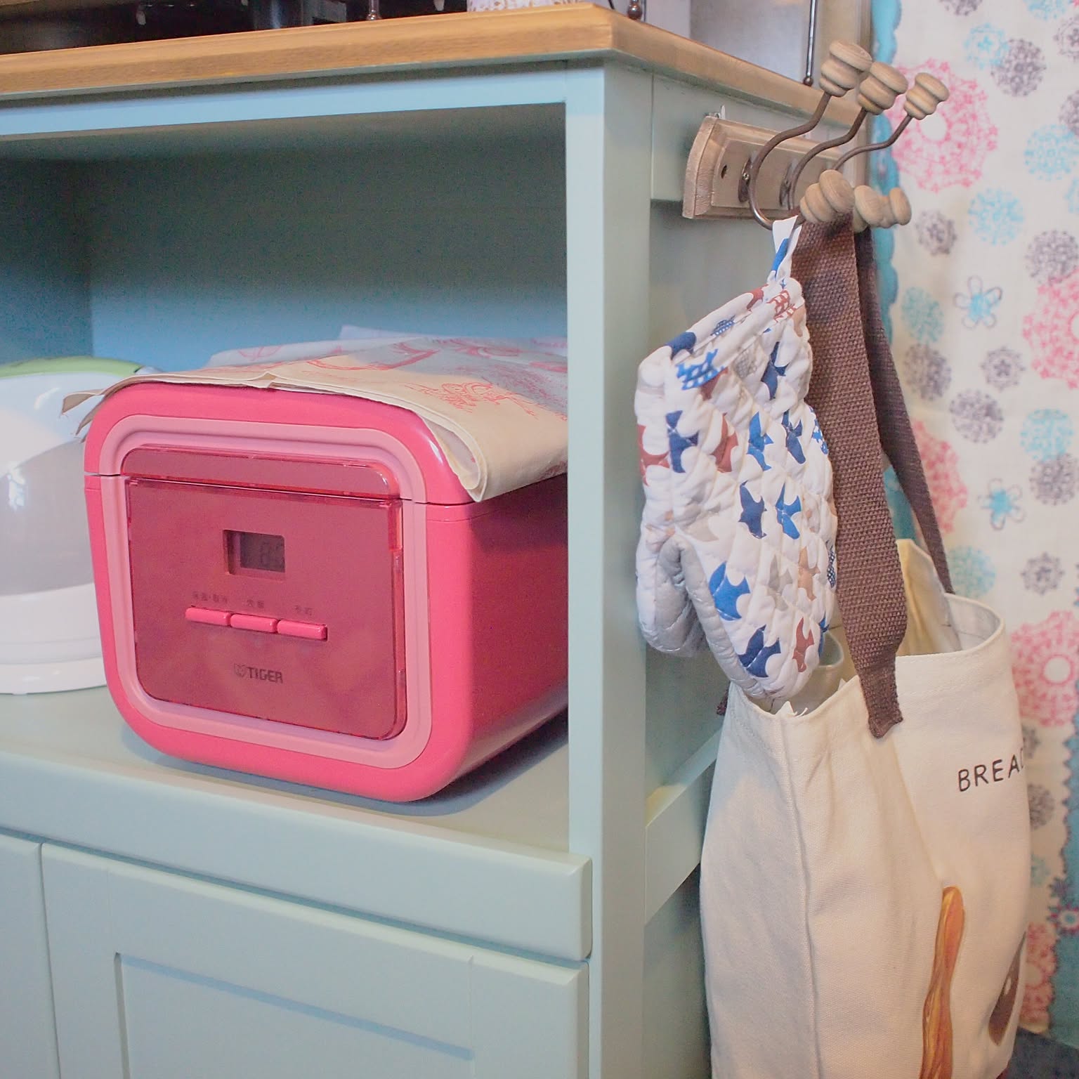A pink Tiger JAJ-A550 compact rice cooker stored on a small shelf.
