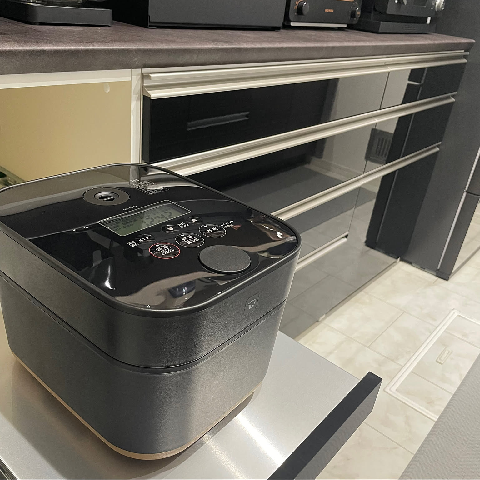A black Zojirushi STAN. 5.5-cup rice cooker placed on a bright counter.