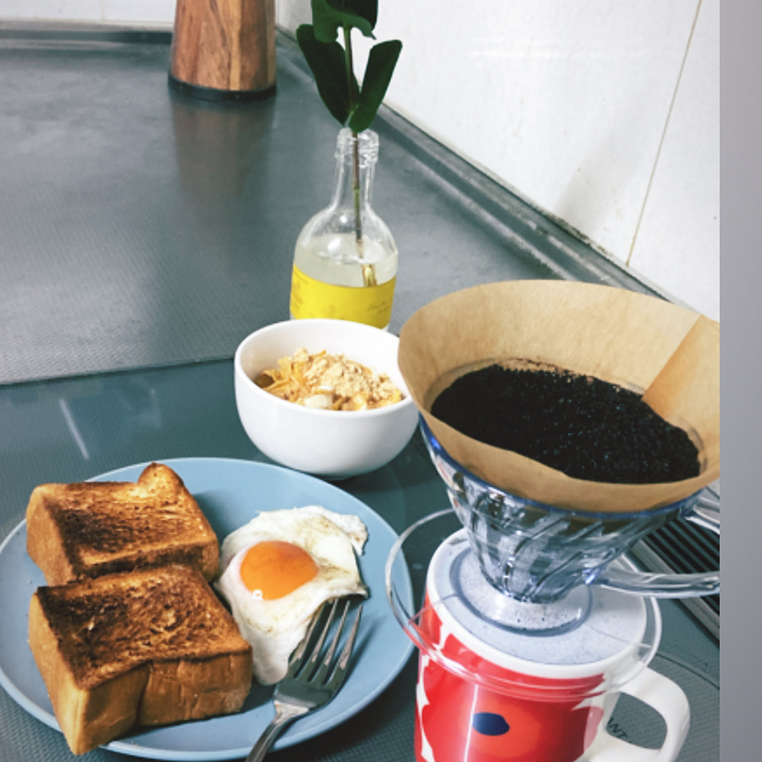 A clear HARIO V60 01 dripper brewing one cup of coffee beside a simple breakfast.
